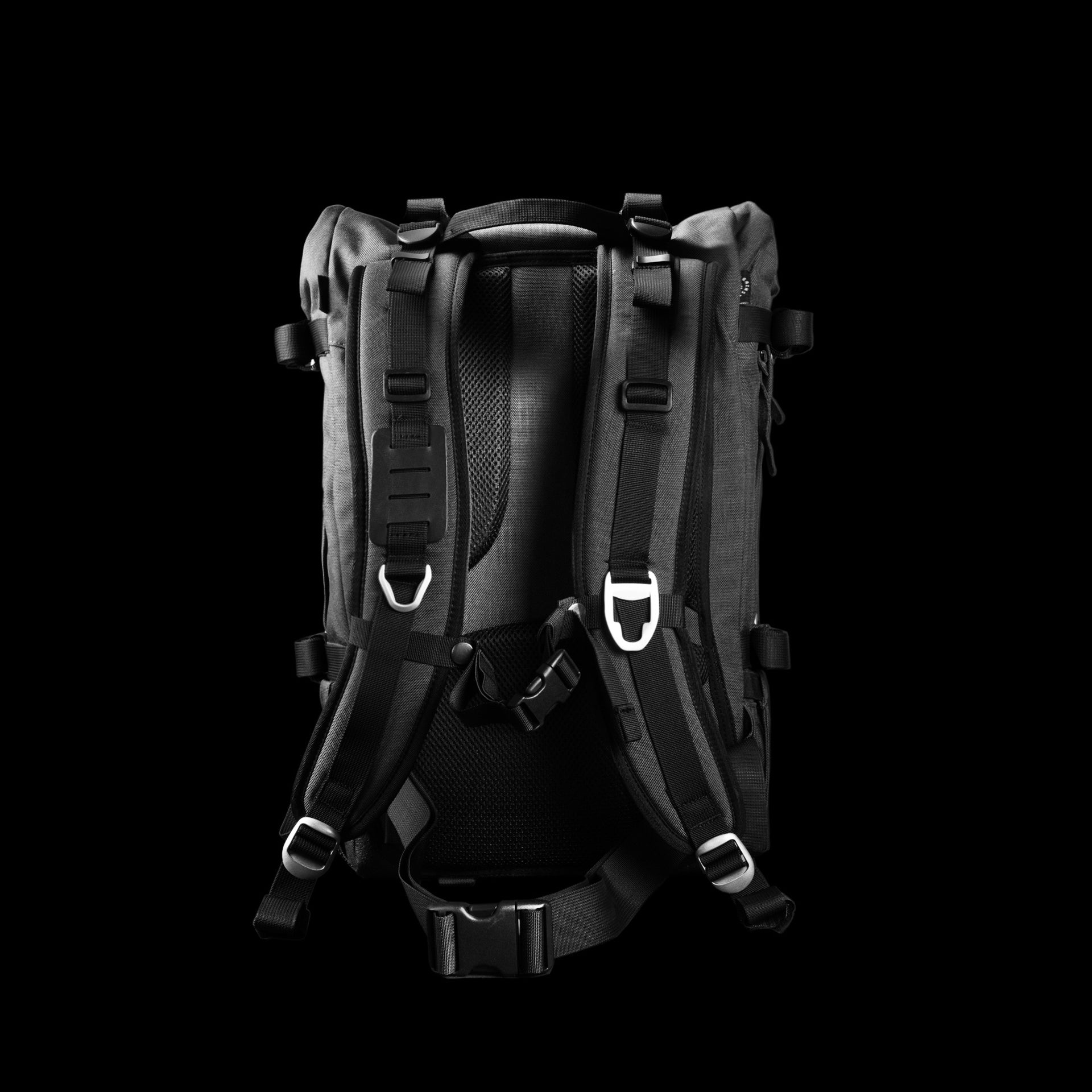 Rear harness of the Asphalt S on pure black, showing sternum strap, hip belt and ventilated back panel.
