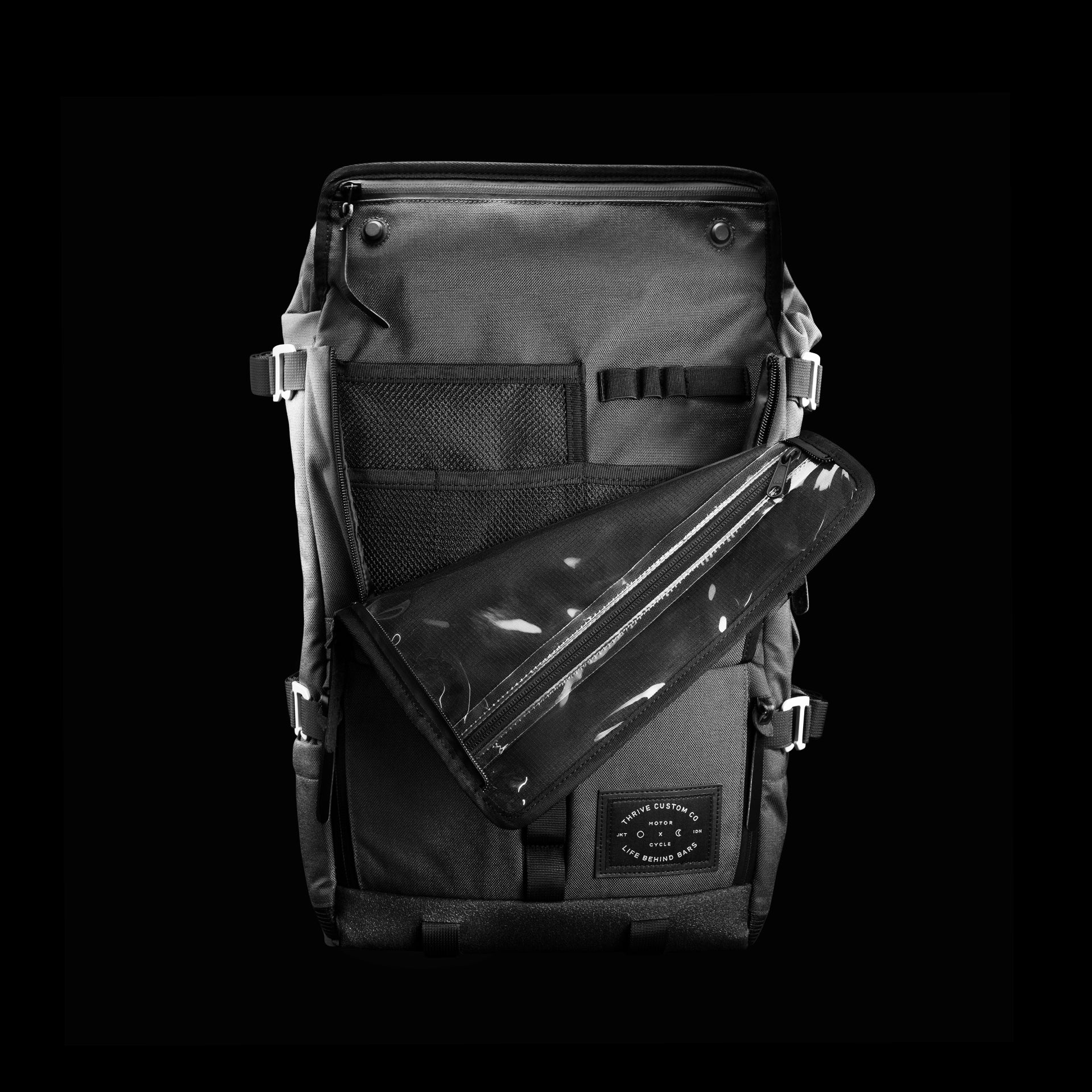 The Peloton Asphalt S opened flat, showing the interior admin panel and hexagonal LBB x Thrive Motorcycle patch, shot on pure black.